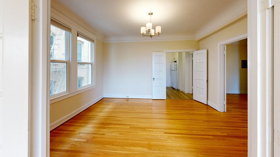 an empty living room with wood floors and white walls